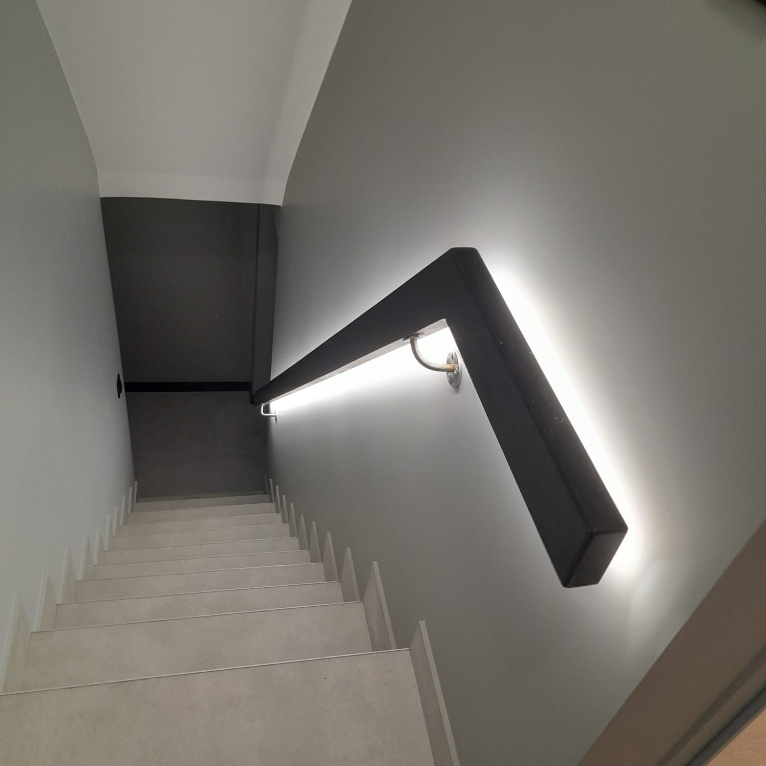 Oświetlenie schodów z poręczą z profilu LED w wąskiej klatce schodowej