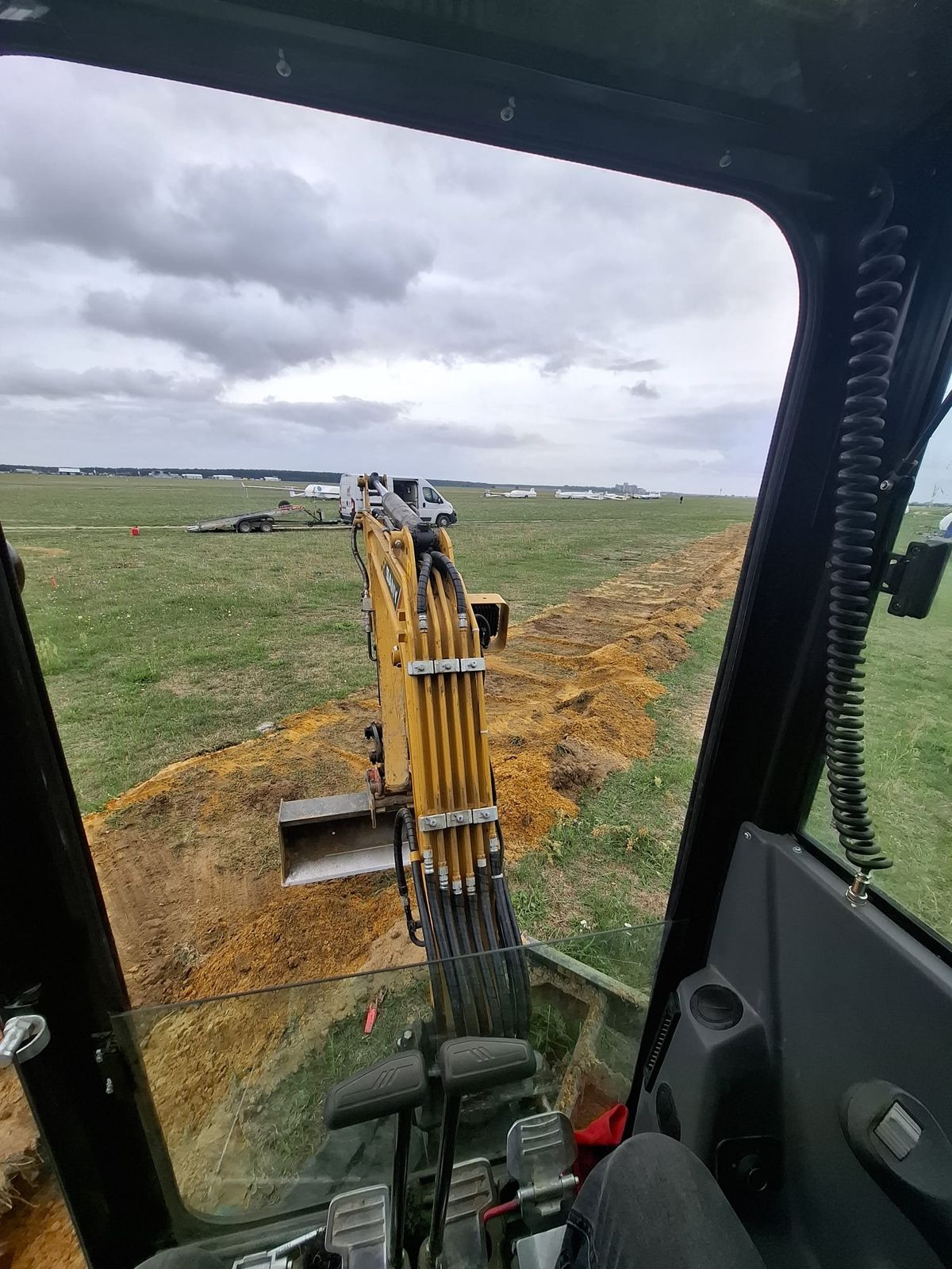 Prace minikoparką przy wykonywaniu wykopu pod trasę kablową na otwartym terenie lotniska